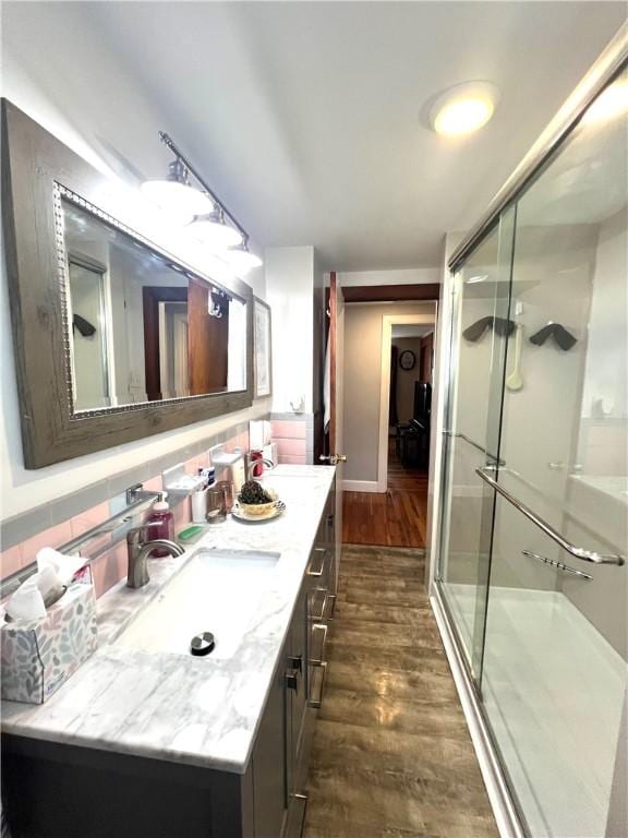 bathroom featuring vanity, a stall shower, wood finished floors, and tasteful backsplash