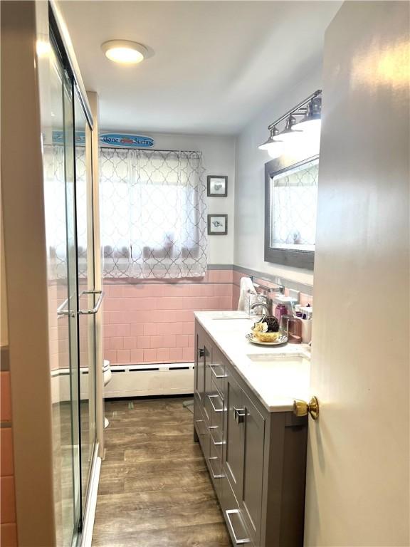 full bath featuring double vanity, toilet, a wainscoted wall, tile walls, and a stall shower