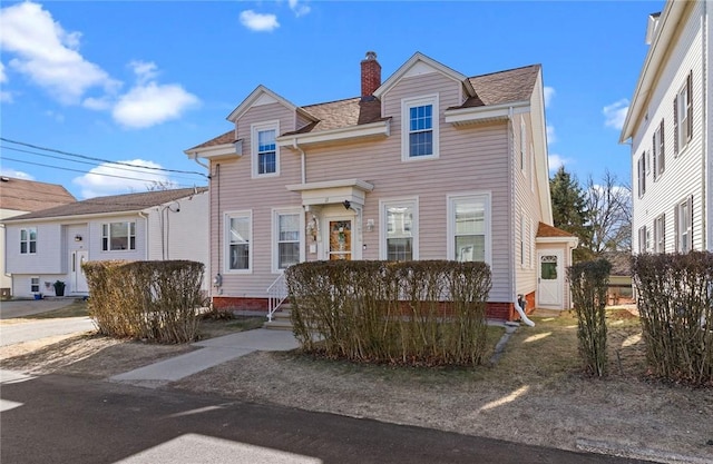 view of front of property with a shingled roof and a chimney