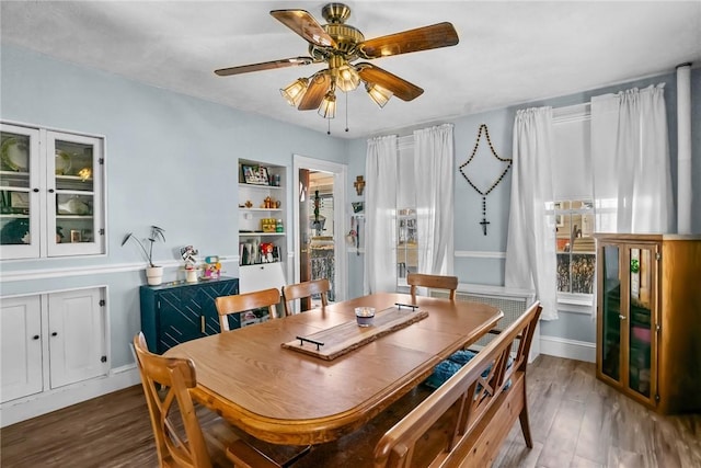 dining space featuring wood finished floors, baseboards, and ceiling fan