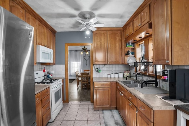 kitchen featuring a sink, white appliances, brown cabinetry, light tile patterned floors, and decorative backsplash