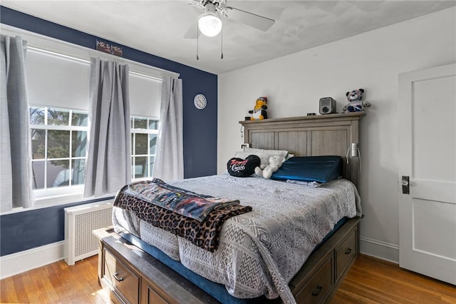 bedroom with radiator, a ceiling fan, baseboards, and wood finished floors