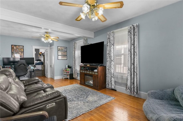 living area featuring ceiling fan, baseboards, and wood finished floors