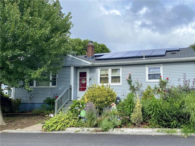 single story home with solar panels and a chimney