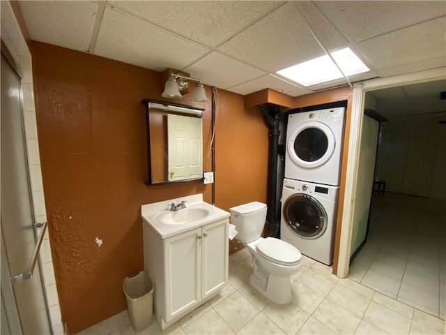 washroom featuring a sink, light tile patterned floors, laundry area, and stacked washing maching and dryer