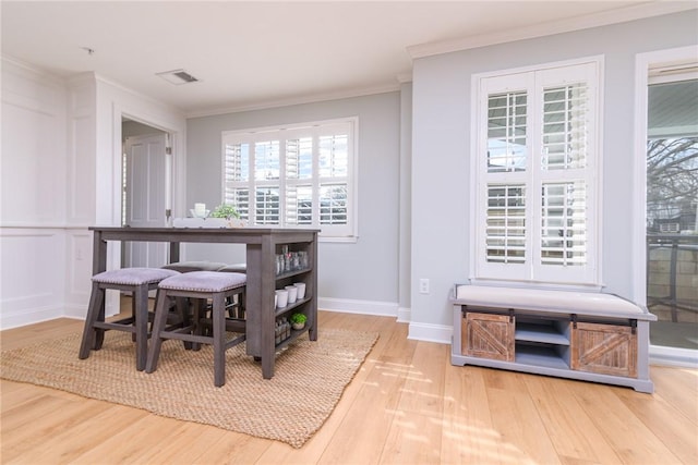 dining room featuring crown molding, wood finished floors, visible vents, and baseboards