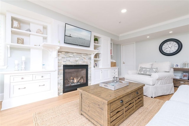 living area with a stone fireplace, crown molding, and light wood-style floors