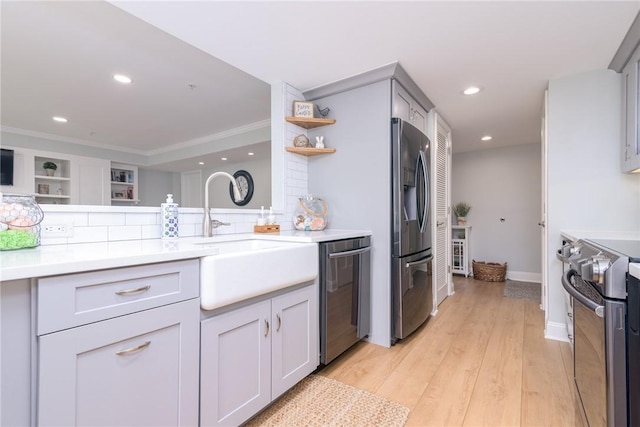 kitchen featuring light wood finished floors, open shelves, recessed lighting, stainless steel appliances, and a sink