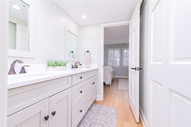 full bath featuring double vanity, wood finished floors, ensuite bathroom, and a sink