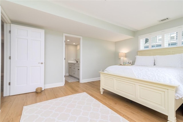 bedroom with visible vents, connected bathroom, light wood-type flooring, and baseboards