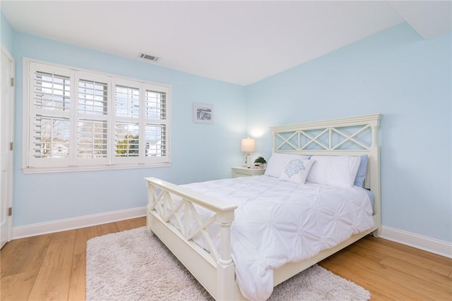 bedroom featuring visible vents, baseboards, and wood finished floors