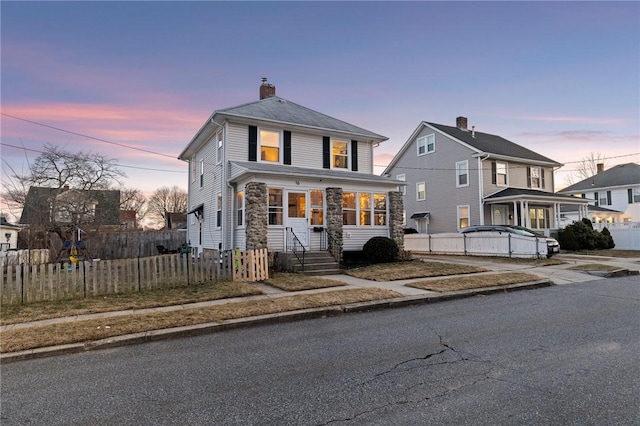 american foursquare style home with a fenced front yard and a chimney