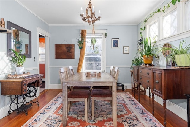 dining room with a chandelier, a healthy amount of sunlight, ornamental molding, and wood finished floors