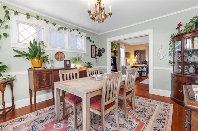 dining area featuring baseboards, an inviting chandelier, wood finished floors, and ornamental molding