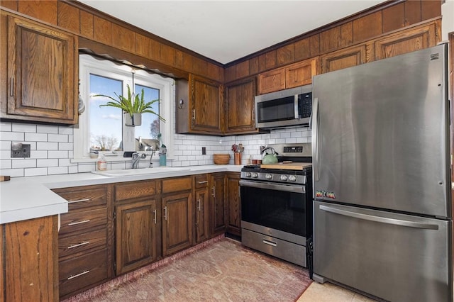 kitchen featuring backsplash, appliances with stainless steel finishes, light countertops, and a sink