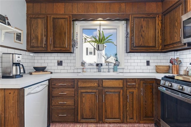 kitchen with tasteful backsplash, stainless steel appliances, light countertops, and a sink