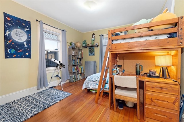 bedroom featuring baseboards, hardwood / wood-style floors, and radiator heating unit