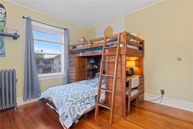 bedroom featuring radiator, baseboards, and wood finished floors