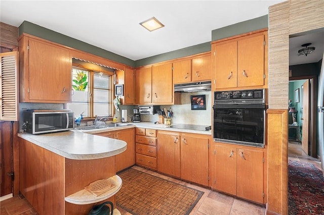 kitchen with black appliances, under cabinet range hood, a sink, a peninsula, and light countertops