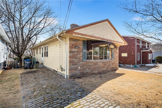 view of home's exterior featuring fence, stone siding, and a chimney