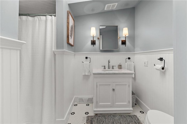 full bath featuring visible vents, wainscoting, a shower with curtain, tile patterned floors, and vanity