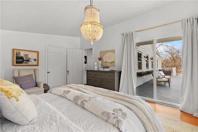 bedroom featuring a notable chandelier, wood finished floors, and access to outside