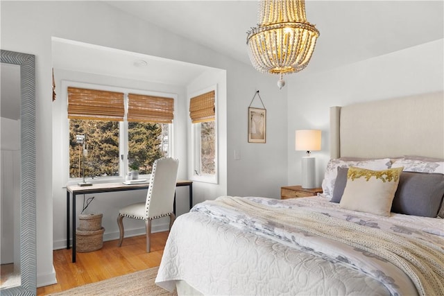 bedroom with an inviting chandelier, wood finished floors, and baseboards