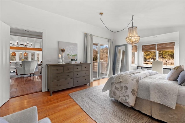 bedroom with access to exterior, a notable chandelier, and light wood-type flooring