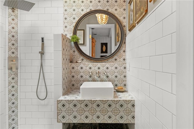 full bath with decorative backsplash, tiled shower, and a sink