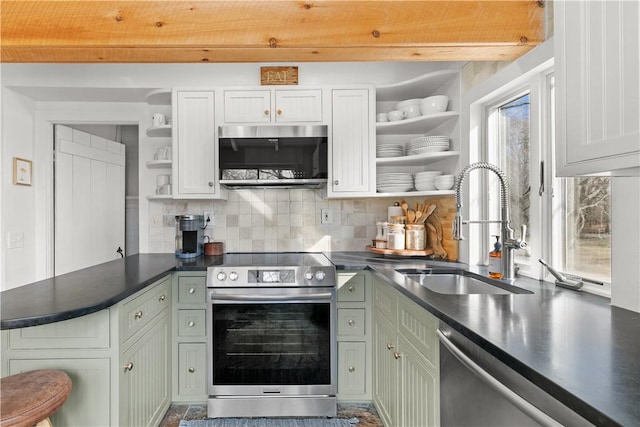 kitchen featuring dark countertops, backsplash, open shelves, appliances with stainless steel finishes, and a sink