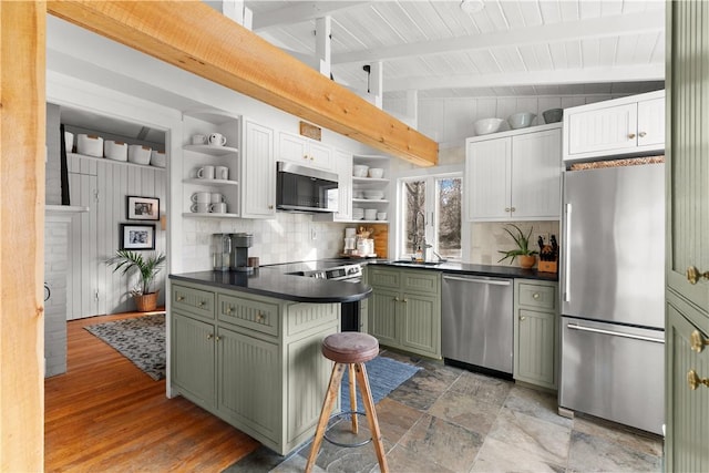 kitchen with dark countertops, appliances with stainless steel finishes, green cabinets, and open shelves