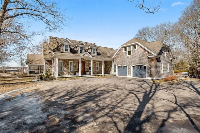 view of front of house featuring stone siding, a porch, and driveway