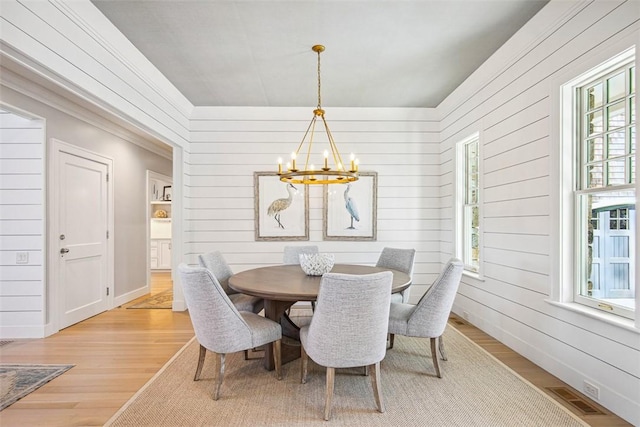 dining area featuring light wood finished floors, visible vents, baseboards, and an inviting chandelier