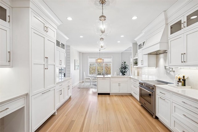 kitchen featuring pendant lighting, light wood-type flooring, light countertops, white cabinetry, and high end stainless steel range