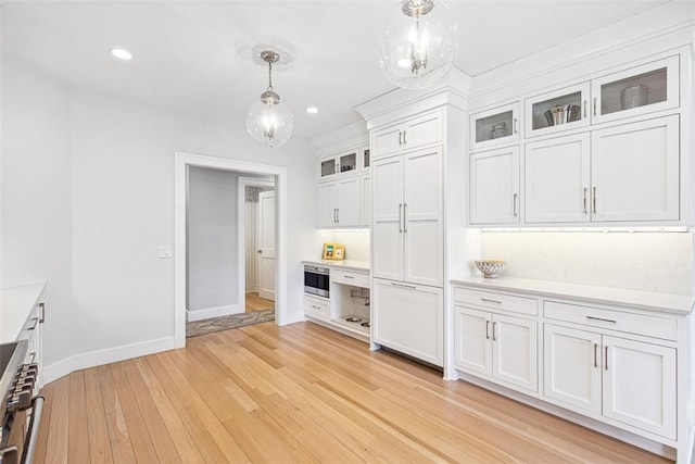 kitchen with white cabinetry, light wood-style floors, light countertops, baseboards, and hanging light fixtures