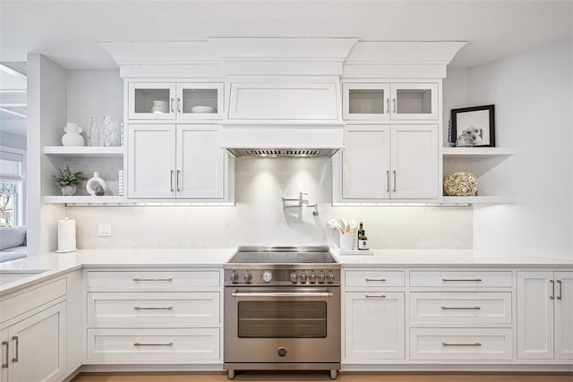 kitchen with open shelves, stainless steel stove, white cabinets, and light countertops