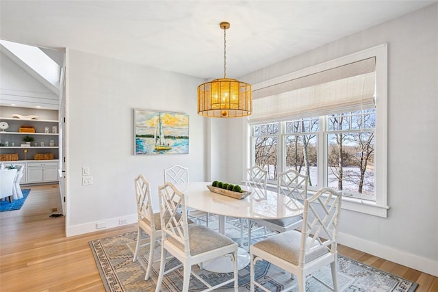 dining area featuring an inviting chandelier, light wood-style flooring, and baseboards