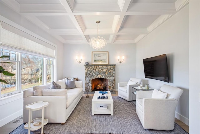 living area with wood finished floors, baseboards, beam ceiling, a fireplace, and a chandelier