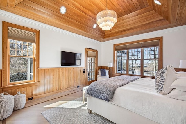 bedroom featuring a chandelier, wood ceiling, wainscoting, wood finished floors, and a raised ceiling