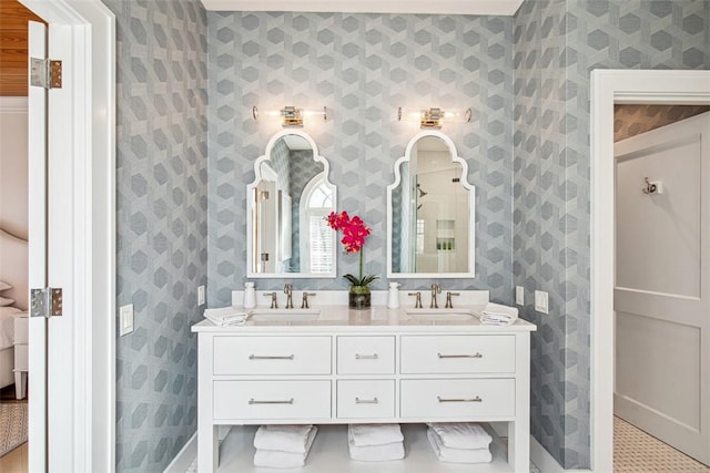 bathroom with wallpapered walls, double vanity, and a sink