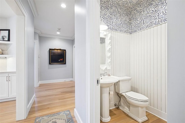 bathroom featuring crown molding, toilet, wood finished floors, and baseboards