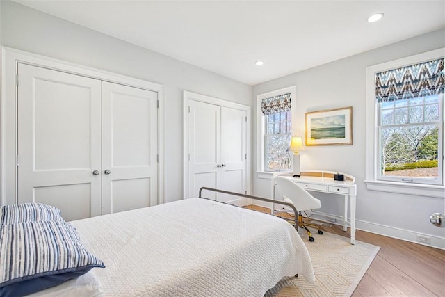 bedroom featuring recessed lighting, two closets, baseboards, and wood finished floors