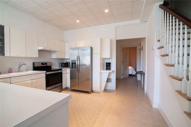 kitchen featuring under cabinet range hood, appliances with stainless steel finishes, light countertops, and a sink