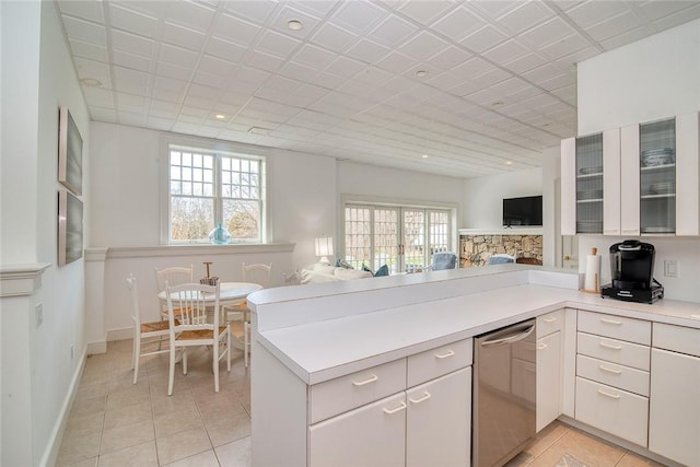 kitchen featuring open floor plan, a peninsula, light countertops, and dishwasher