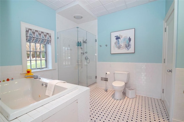 bathroom featuring a shower stall, a jetted tub, toilet, and tile walls