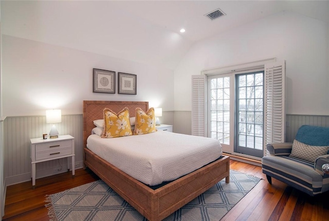 bedroom with a wainscoted wall, multiple windows, visible vents, and vaulted ceiling