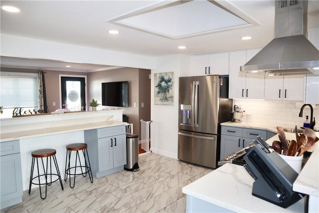 kitchen with stainless steel fridge with ice dispenser, island exhaust hood, a sink, a kitchen breakfast bar, and marble finish floor