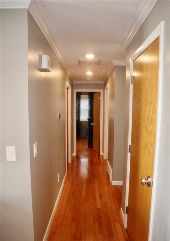 hall with baseboards, wood finished floors, and ornamental molding