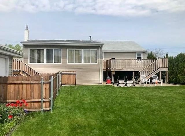 back of property featuring stairs, a deck, a lawn, and fence