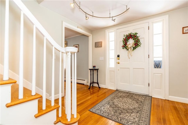 foyer with baseboards, a baseboard heating unit, stairs, and light wood-style floors